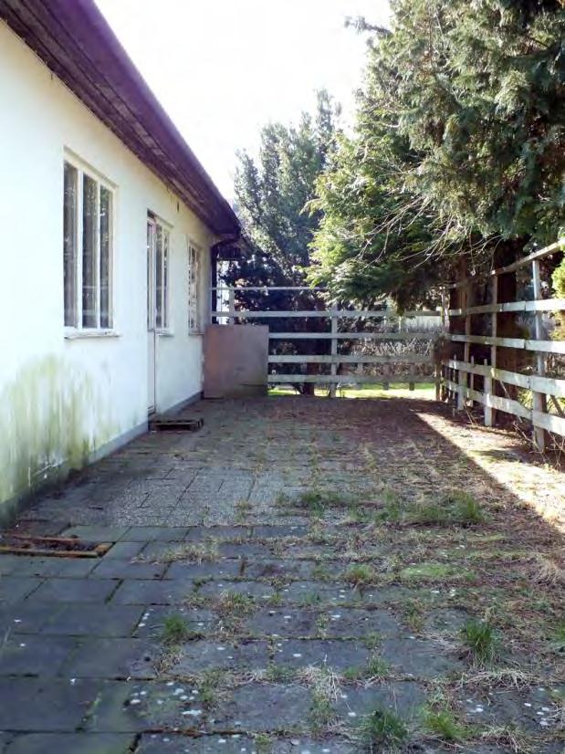 Hantverkföreningens hus; till vänster uteplatsen längs byggnadens västra långsida och till höger utblick över parkeringen nordväst om huset.