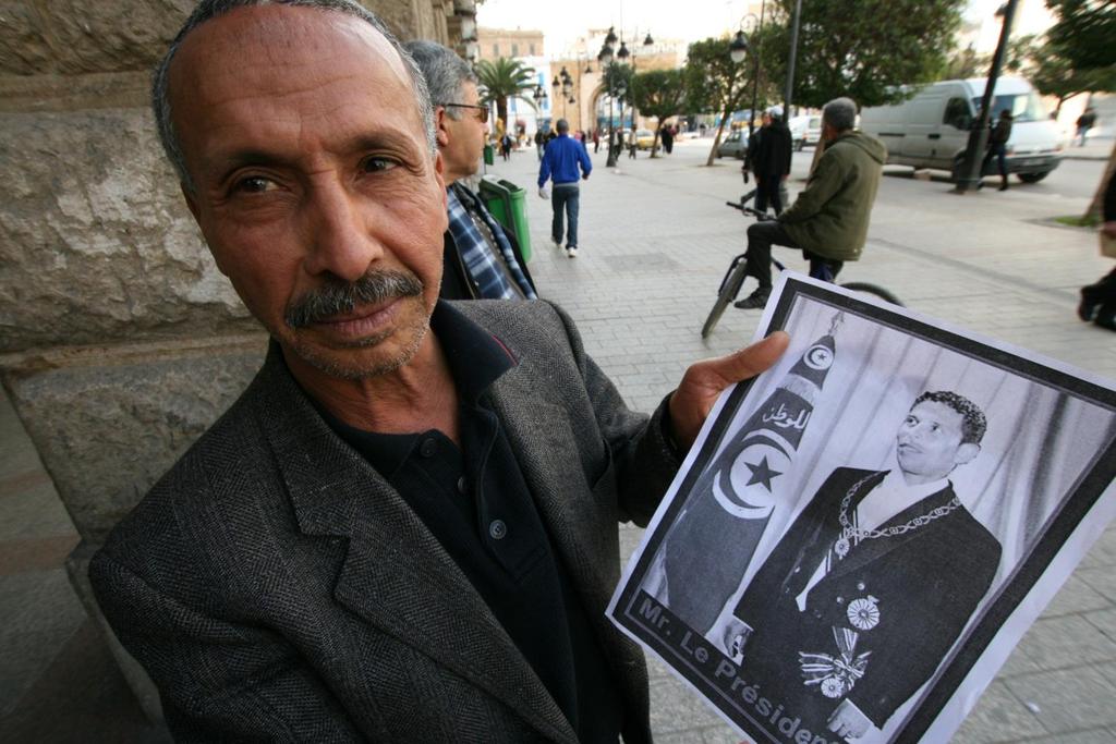 Mannen på gatan i Tunis håller upp ett bildmontage av Mohammed Bouazizi,
