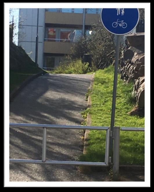 av höga staket, få fönster mot gatan och berg som omgärdar gång och cykelväg in mot Badhusberget.