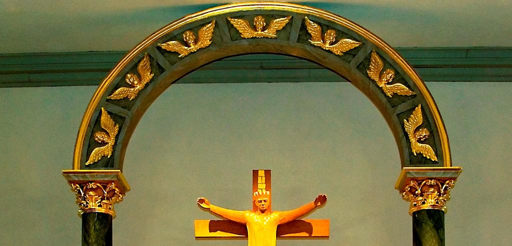 Korskulptur-Altare- vid norra långsidan- Under rundbåge, med änglahuvuden uppburet av två kolonner av Hans Biskop, finns korskulptur som visar den segrande