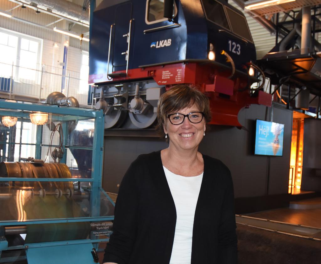Produktionskunskap Teknikens Hus verksamhetschef, Kristina Jonsson, i den stora verksamhetshallen. Bredvid henne står en pappersmaskin som gör ett riktigt papper.