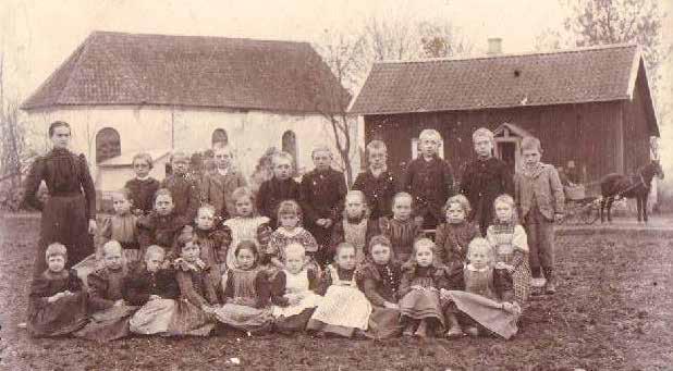1898 års småskoleklass framför Fåglums Kyrka och Sockenmagasin Lärarinnan på bilden heter Emma Svensdotter Eklund, född 1864 i Naum.