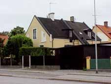 ½ Svartmålad sten. Gul spritputs. Sadeltak, svart korrugerad papp. Mörkbruna 2-lufts fönster med tvärspröjs.