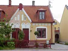 Rundade vita fönsteromfattningar. Vit dörromfattning med dubbelbåge. Vita rundade utsparningar i dekorband. Vit avtrappad gesims. Vita stora dekorutsparningar mot söder.