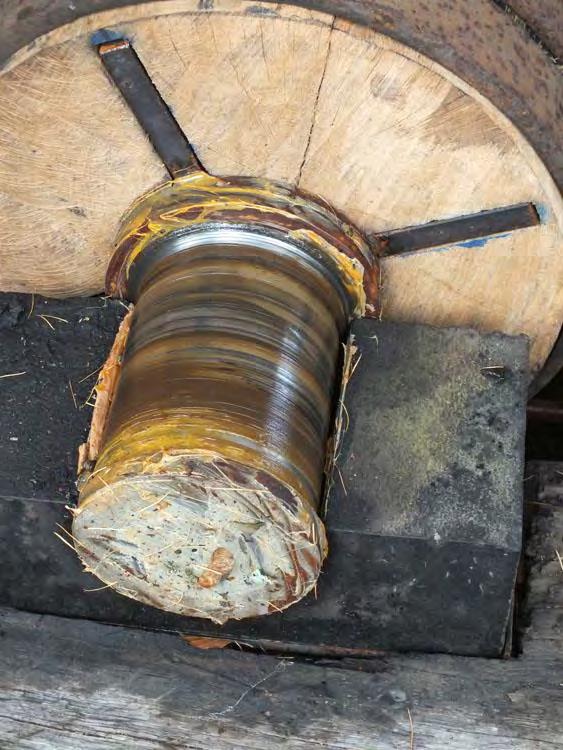 Till höger detalj av nålen, som centrerats i axeln, smorts och nu är stabilt förankrad i blocket. Val av virke och sågning Virket till det nya vattenhjulet är av tätvuxen, norrländsk fur.