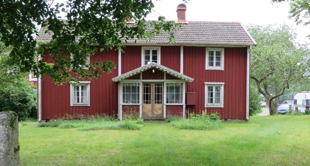 Mellangården har äldre fönster och glasveranda. Trädgård med stenstolpar och brunn (Lida 1:18).