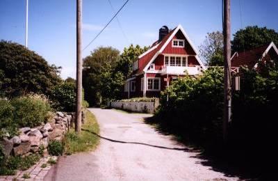 Gles bebyggelse med lummiga trädgårdar kantar vägarna. Husen har enkla volymer med träfasader eller mer reslig karaktär där havsutsikten ger ett extra plus till översta våningen.
