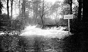 Troligen byggd på 1860 talet. Foto från 1930 talet. Då nya väg 49 byggdes 1958 revs den och ersattes med en betongbro. Bilden tagen från platsen för den gamla kvarndammen.