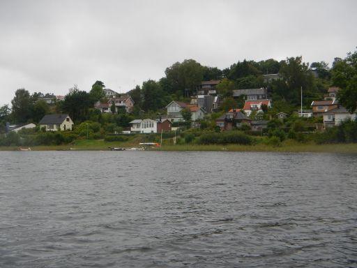 Figur 77. Foto över omgivning dominerad av tomtmark vid Rådasjön. Figur 78. Strandlinje i Rådasjöns nordöstra del där häll förekommer.