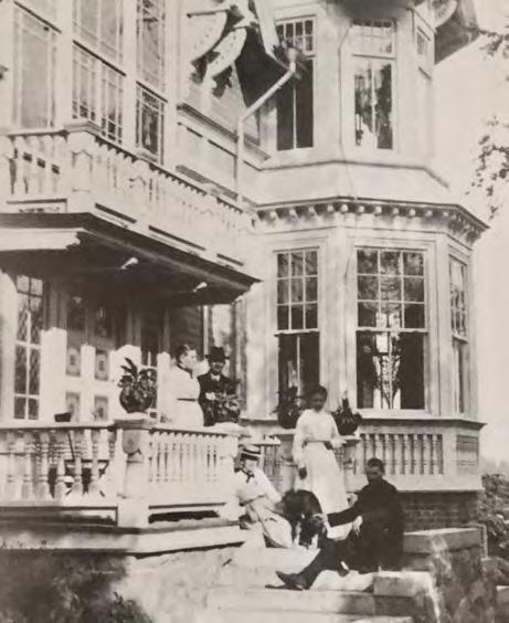 En vacker sommardag i början av 1900-talet vilar familjen och några gäster ut på trappan vid husets entré. mang och det fantastiska hallfönstret.