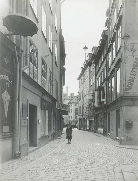 EN LITEN FLICKA STÅR UTANFÖR LATONA 10, DÄR EN SKYLT ANNONSERAR SKOUT- FÖRSÄLJNING. OKÄND FOTOGRAF CA 1915. STADSMUSEETS ARKIV, FA 49213.