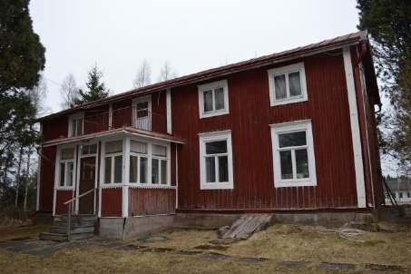 plats invid Strandvägen. Det består av huvudbyggnaden och en ekonomibyggnad. Framför byggnaderna finns öppet landskap.
