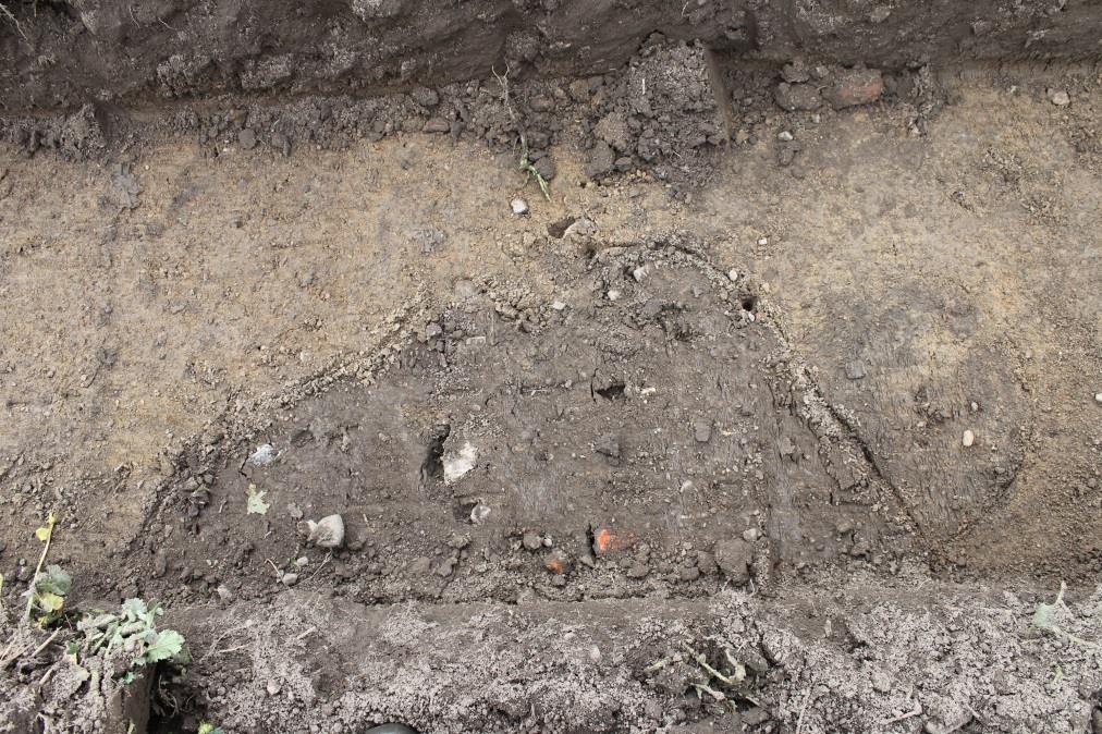 Figur 20. Omkring nio meter från schakt 7:s södra begränsning fanns en grop med inslag av tegel. Omedelbart norr om gropen fanns ett stolphål. Foto från öster. Foto: Lars Jönsson, Österlenarkeologi.