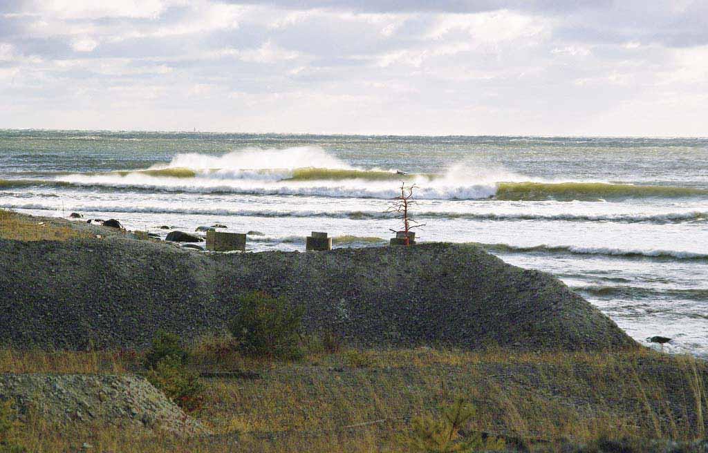 Sahara Schaktmassor, kalkstenskross och järnskrot Nordostliga stormvågor rullar in mot Saharaområdets strand, en strandlinje som är skapad under kalkindustritiden med utschaktat spillmaterial från