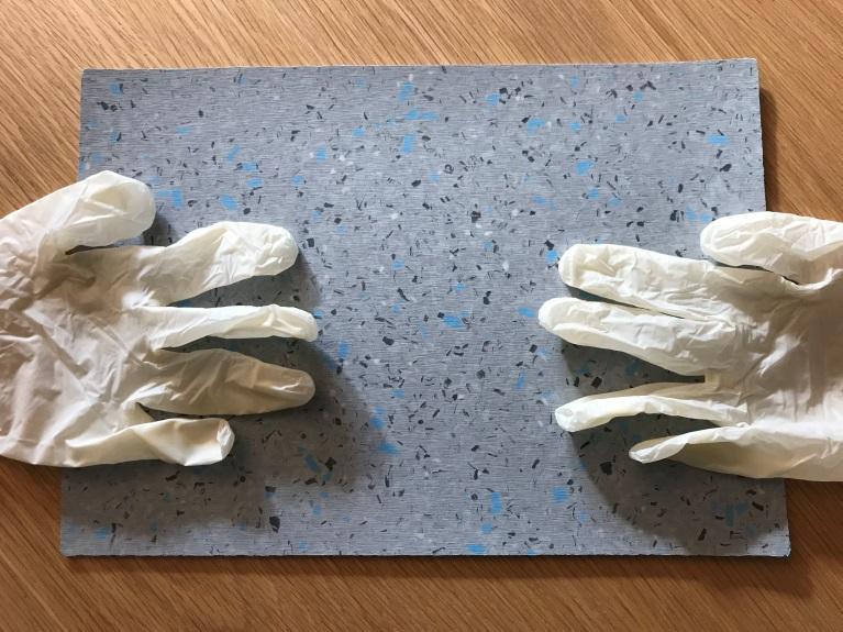 Figure 10. The produced compound (in bag) containing 20 % of pre-treated and recycled PVC from vinyl gloves and a produced floor sample partly based on the compound.