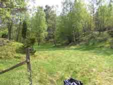 Ravinbildningarna saknas och det lilla vattendraget rinner här fram över ett flackt, smalt och öppet, kultiverat landskap som omges av branta bergssluttningar.