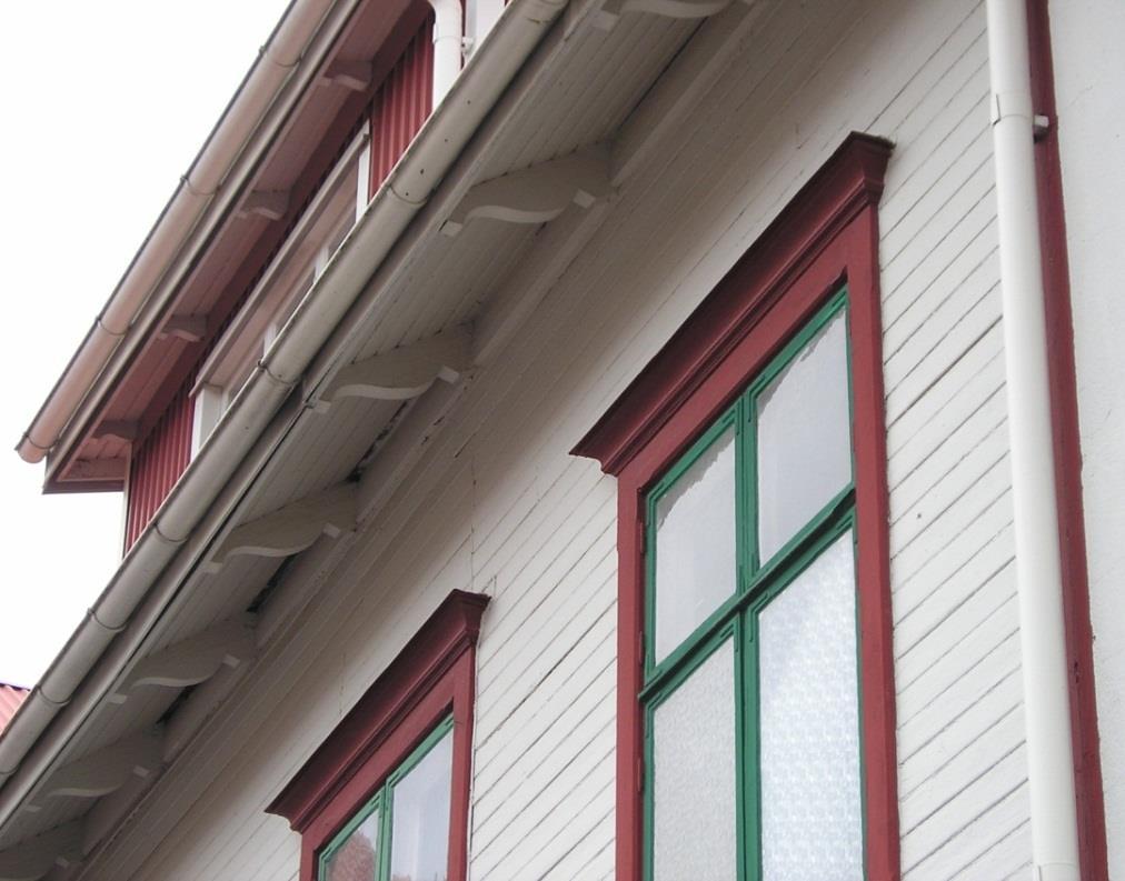 Detaljer, som de gröna träfönstren med engelskt röda profilerade omfattningar med markerade krön och takfotens