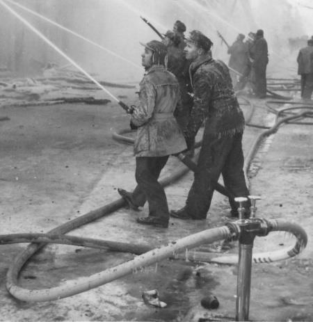 Bilden en brand med nedisade slangförare och istappar på slangar. Det var när Assembléhuset i Kristinehamn brann 1955. Arbetet i kyla och snö är tungt och kan vara farligt halt.