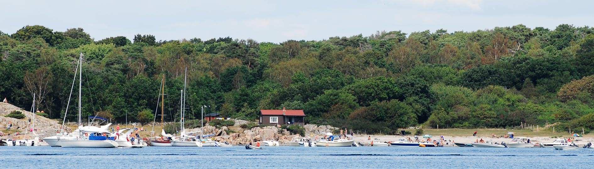 Kyrkogården med "Göstas (Johnsson) kors" i maj 2006. John Nygrens foto från öster. Vy över Lilla Sandhamn från nordväst med den ringlande stigen och klipporna med Smygan (skymd). Foto John Nygren.