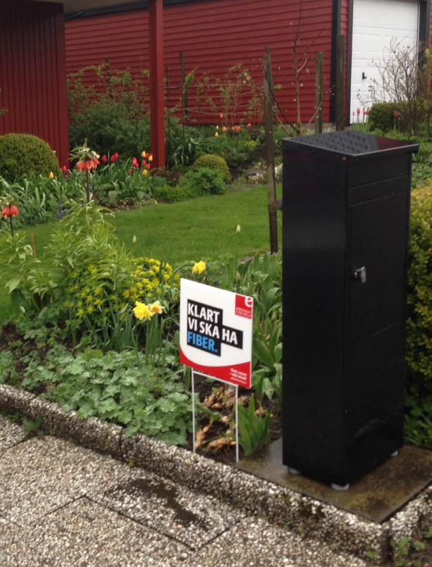 Håltagningspunkt för fiberkabel samt placering av fasadskåp markeras på husväggens utsida. Röd markeringskäpp sätts vid husgrund.