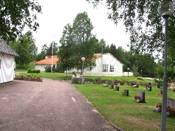 I väster, mot församlingshemmet och minneslunden avgränsas tomten av häckar. Ingångar till kyrkotomten finns i alla väderstrecken.