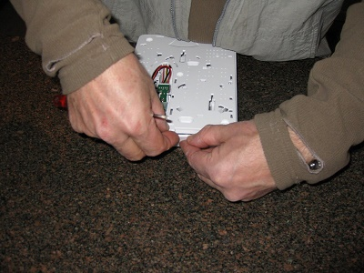 Lossa skruven på det kombinerade väggfästet/fibertrayen. Tag loss locket/väggfästet.
