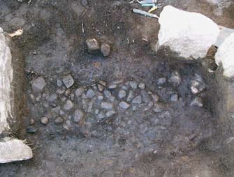Fig. 28. Stenpackning i förrummet, den sista framrensade nivån innan kistbotten, orörd mark, nåddes. Mitthällen syns till höger i bilden. Foto: UV Väst.