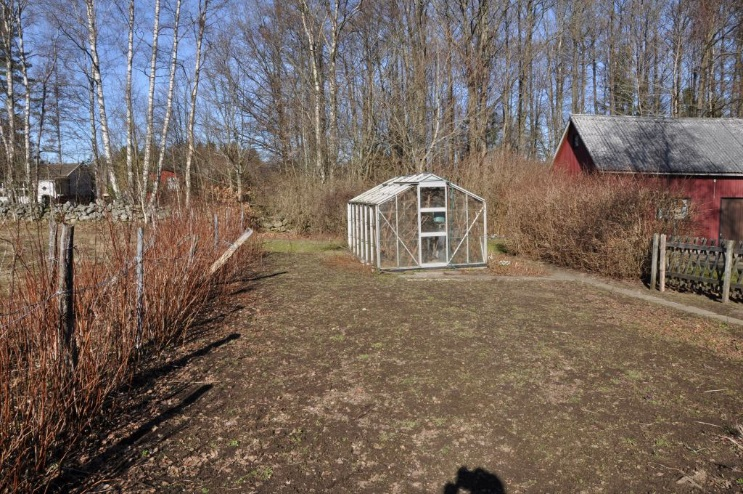 Stor uppvuxen trädgård med överbyggd uteplats och trädgårdsland med centraluppvärmt drivhus. Massor med fruktträd och en bit bort i backen trevlig stensatt jordkällare.