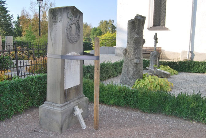 Medelhög gravvård. 2. Gravvård av rödbrun slipad och polerad granit. Medelhög gravvård med brutet krön. Monterad på hög sockel av granit. Inskriptioner inhuggna. Dekor i form av ett latinskt kors. 3.