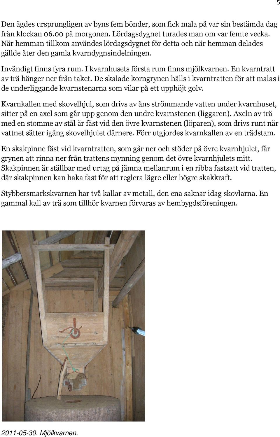 En kvarntratt av trä hänger ner från taket. De skalade korngrynen hälls i kvarntratten för att malas i de underliggande kvarnstenarna som vilar på ett upphöjt golv.