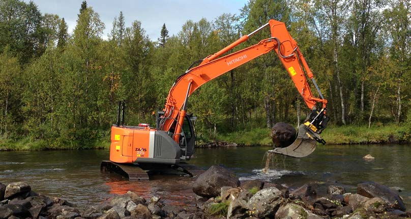 En grävmaskin har hämtat en stor sten från land och placerar den i vattendraget. Foto: Johanna Gardeström bestånden av öring klarar sig på lång sikt.