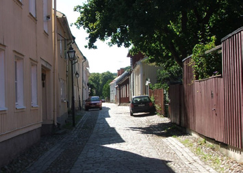 Röda staket vid röda hus skapar en samanhållen färgbild. Olika färgpigment och färgbaser på bostadshus och staket ger olika nyanser.