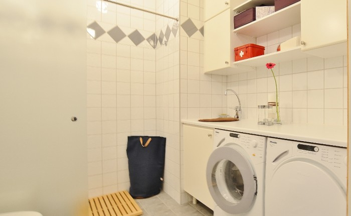Badrum/tvättavdelning Modernt badrum inrett med vita helkaklade väggar med inslag av grått som matchar klinkergolvet.