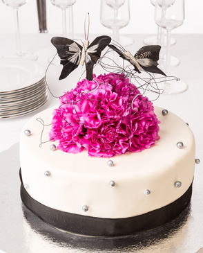 BUTTERFLY Tårtan täcks med vit marsipan och dekoreras med nejlikor och svävande fjärilar. Nejlikor finns i följande färger att välja på: Ljusrosa, ceriserosa, vita eller mörklila.