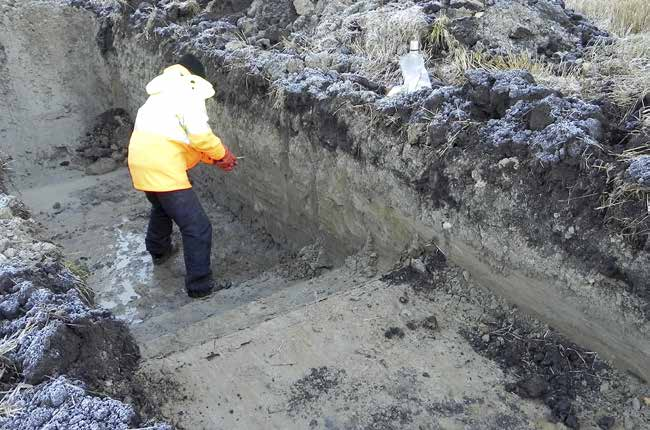 Figur 8. Bengt Nordqvist rensar schaktväggen. I nivå med Bengts fötter kom under den postglaciala leran ett transgierat gruslager som innehöll bearbetad flinta. Foto: Gisela Ängeby.