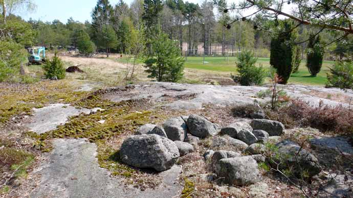 Illustration 6. Norra utredningsområdet. Stensättningen 1081:13, till vänster schakt 6 på en liten del av den forna jordbruksmarken som inte tagits i anspråk för golfbanan. Foto mot sydost.