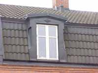 Brun lamelldörr med fönster och stående panel. Mansardfönster klätt med svart plåt, profilerad och med facett.