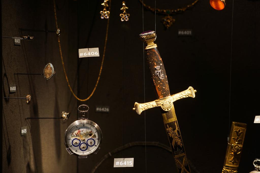 En brokig samling smycken, fickur och ett hederssvärd är monterade för att likna