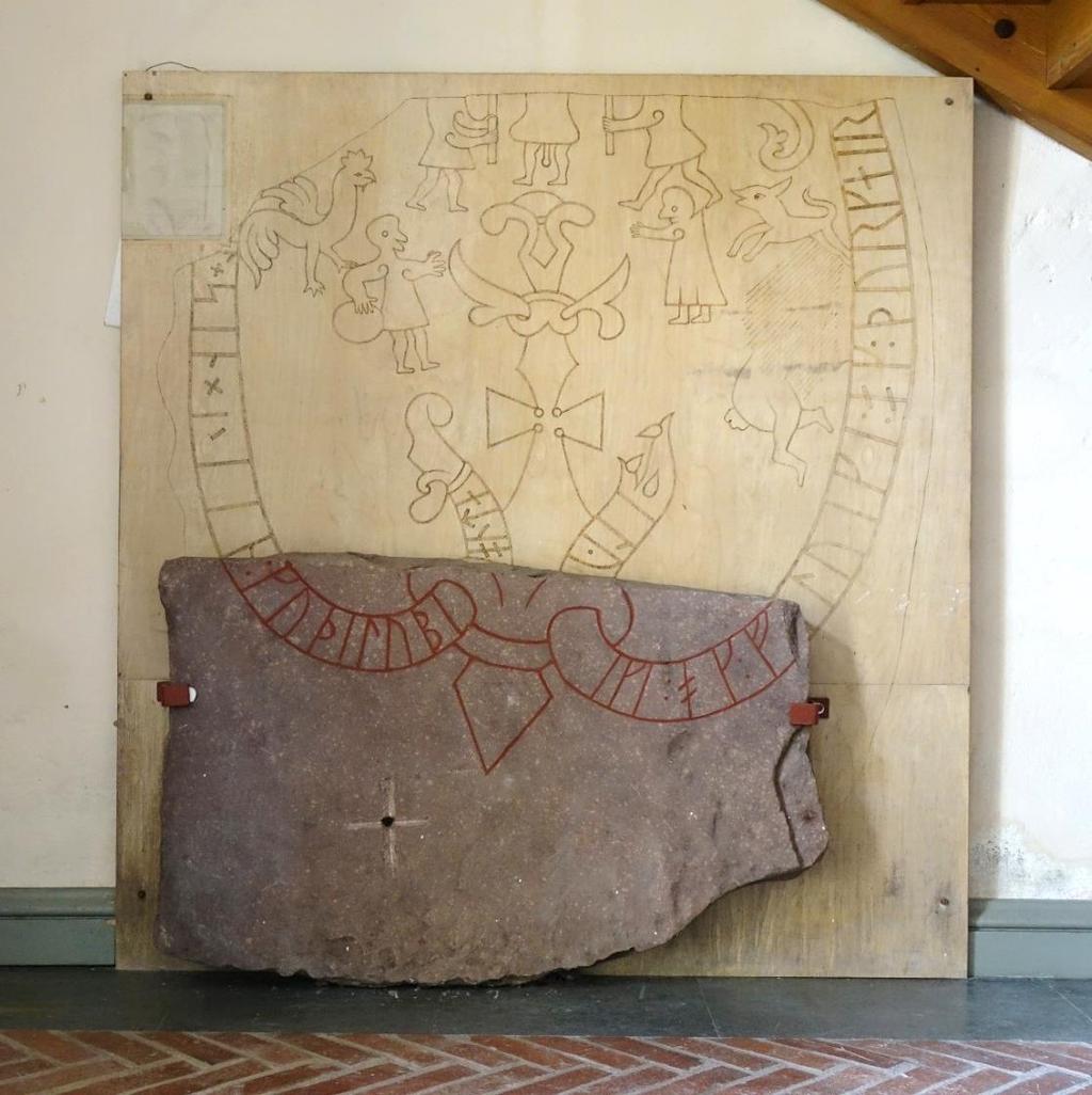 Runstenen är uppställd på ett lågt tegelfundament inne i vapenhuset till Österfärnebo kyrka. Stenen är i röd sandsten.