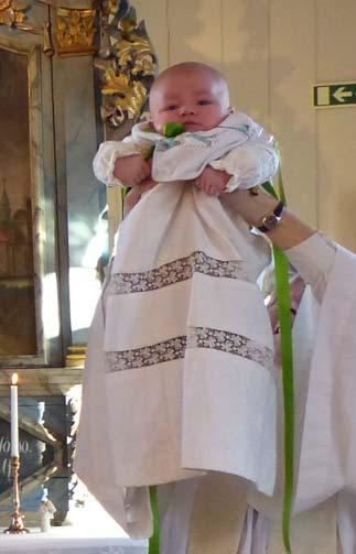 Dopklänningen är alldeles för lång, en symbol för att dopet och den kristna tron är något att växa i. Vitt är glädjens färg.
