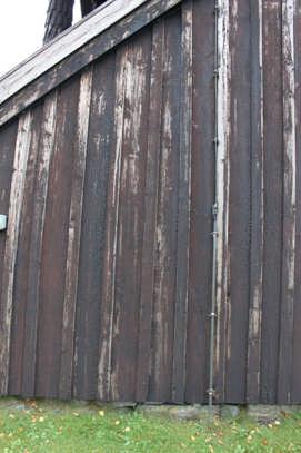 Panel Boden har en stående locklistpanel. Panelen är tjärad och det finns synliga spår av rött både på bottenbrädan och locklisten. Det yttersta lagret trätjära är svart till sin färg.