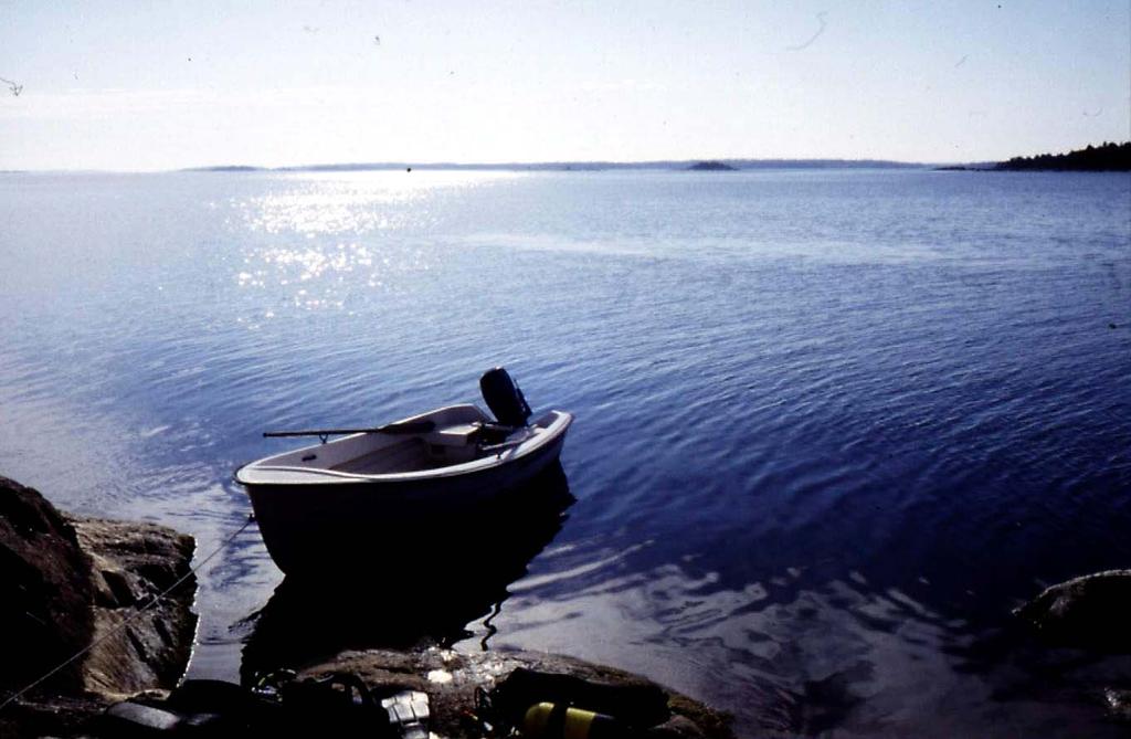 Ur dagboken: 960927 Lätt soldis. Havet ligger blankt Båten ligger för ankar i sundet mellan Skommaren och den fågelskyddade Skommarhällan med sin lilla vita fyr.