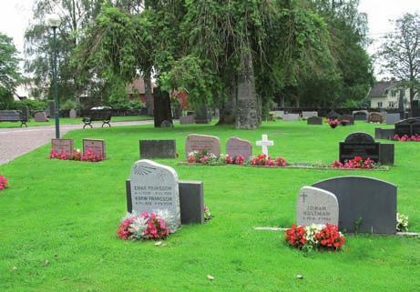 Till vänster en obelisk i diabas och två hällar som ingår i en grusgrav med stenram runt.