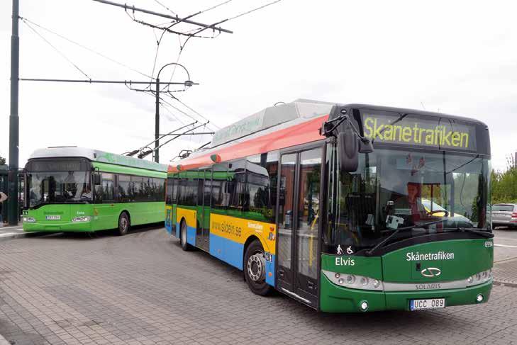 Slide In-bussen i batteridrift med rekonditionerad äldre trådbuss i bakgrunden. Bilden är tagen vid hållplatsen Stationen 30 juni 2016.