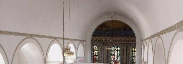 Digitalfoto Rolf Hammarskiöld Kyrkorummet har ett mittskepp med stort slätputsat vitt tunnvalv, på var sida buret av sex tjocka, rosakalkade kolonner, med gråkalkade baser och kapitäl.
