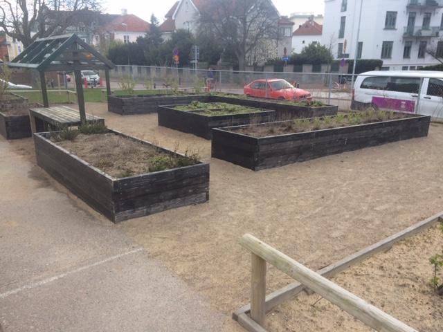 den närliggande bilvägen. Markmaterialet varierar från sand inom området med gungställning till stenmjöl i området med odlingslådor.