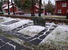 samt något rundade hörn. Slät framsida med förhöjd text och ett förhöjt kors. Gravstenen står på en liten stensockel. Helena Schukowitsch, 1892-1981.