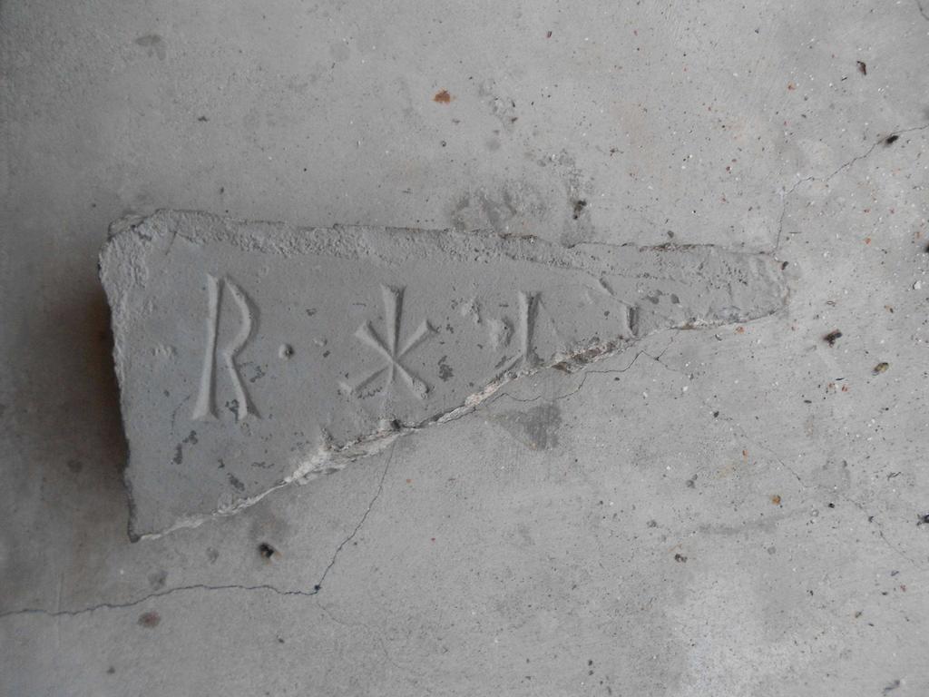 På den ena sidan finns spår av bruk, medan den andra är glattare, vilket tyder på att fragmentet har legat som golvsten.