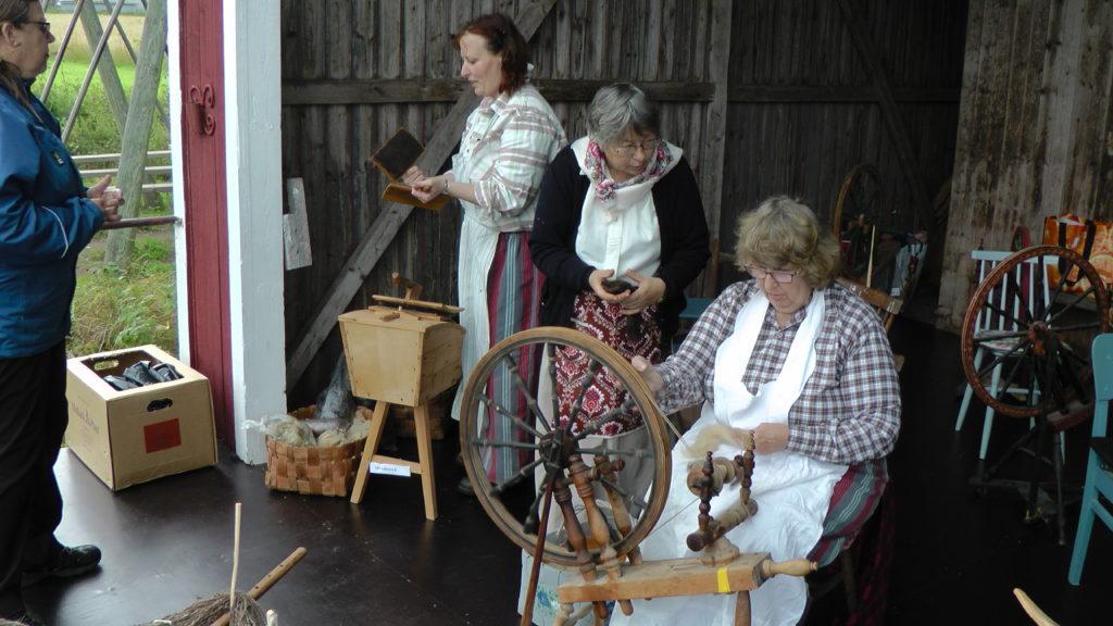 I bakgrunden vid skrubbänken förklarar Anne hur det går till att karda.