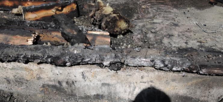 7 Förkolnad balk vid golvet mellan målerihall och verkstadshall. Bild 4. Den förkolnade träbalken på golvet. Bild 5. Opåverkad ventilationsfläkt.